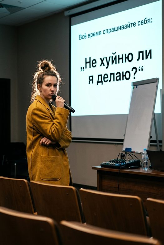женщина спикер у экрана проектора с микрофоном