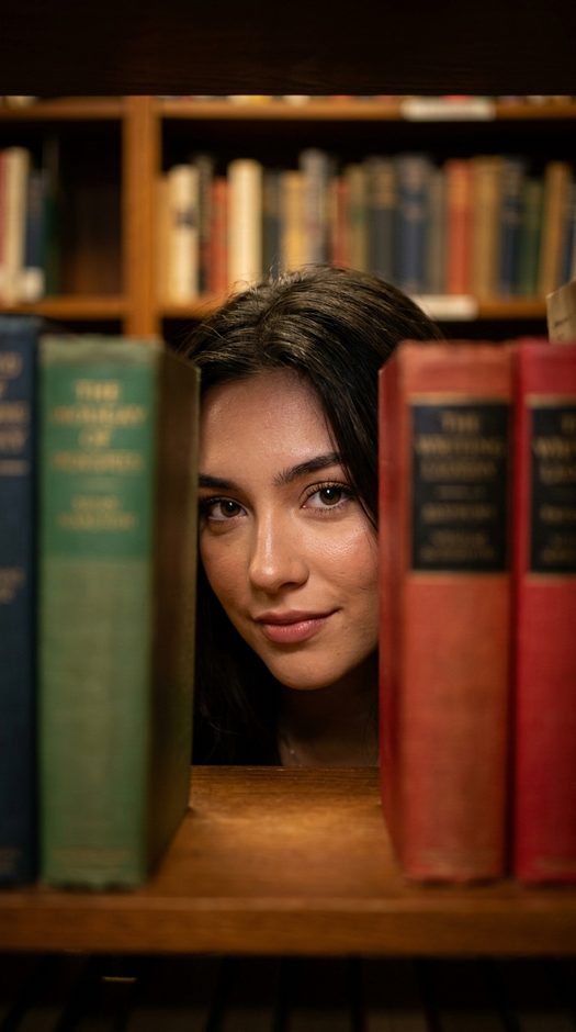 девушка между книгами в библиотеке